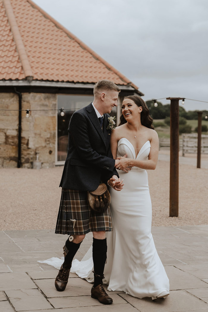 bride and groom laugh outside falside mill