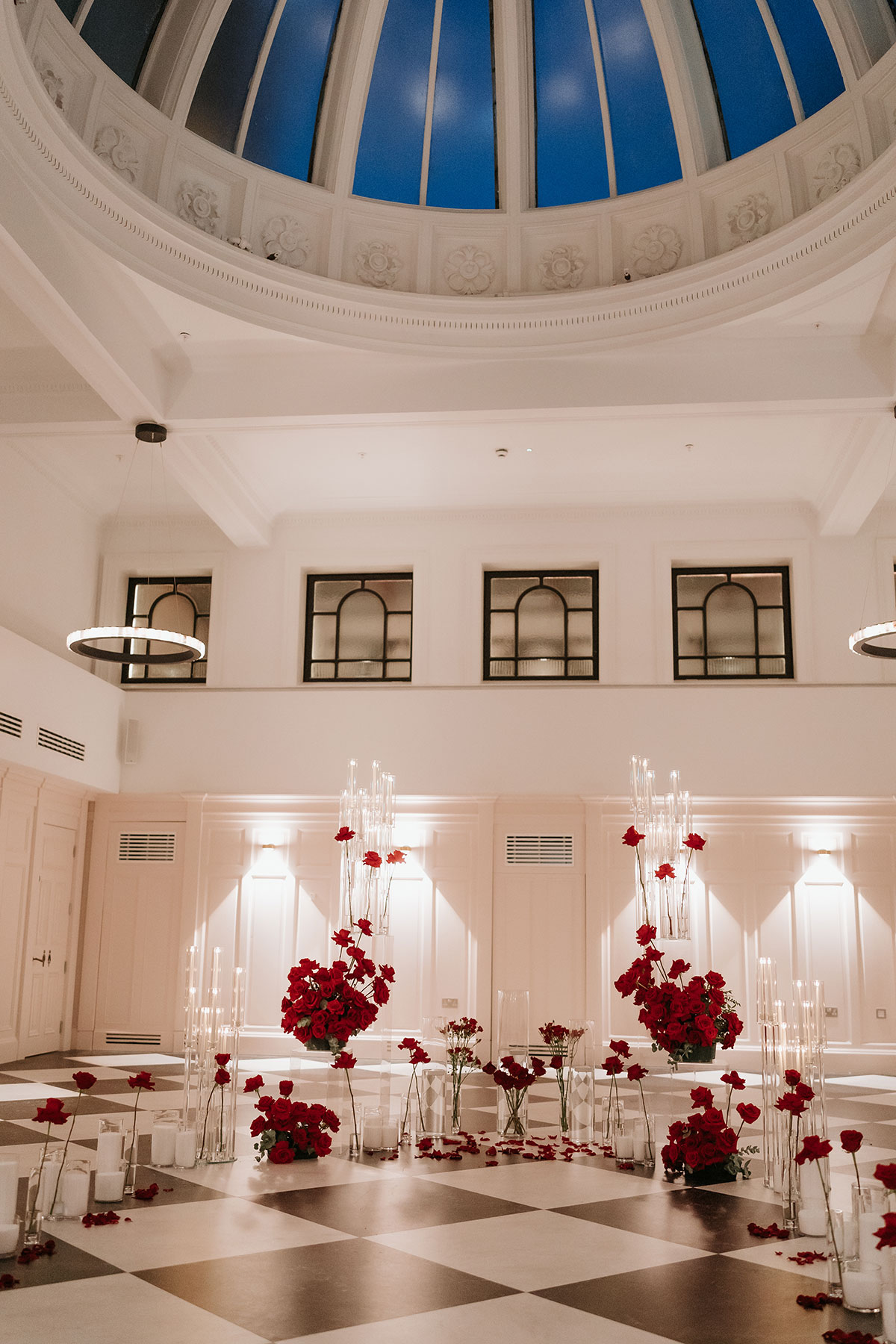 Red rose engagement proposal styling beneath a dramatic glass dome ceiling