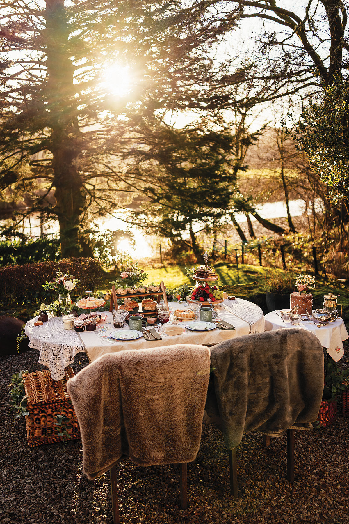 Romantic outdoor wedding picnic with afternoon tea, fresh flowers and lakeside views bathed in golden sunlight