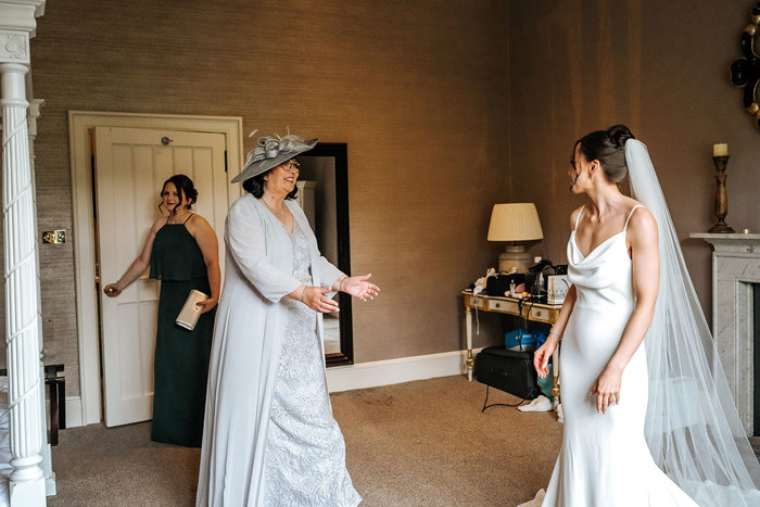 bride smiles as mum comes into hotel room for first look on wedding day at mar hall