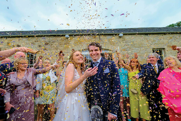 Wedding Guests Throwing Confetti On Happy Couple