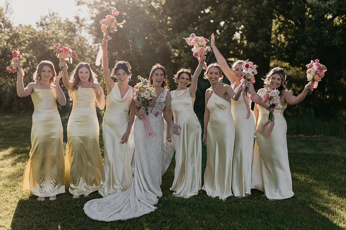 Bride celebrating with seven bridesmaids in butter yellow satin dresses at Boschendal Wine Estate wedding in Cape Town