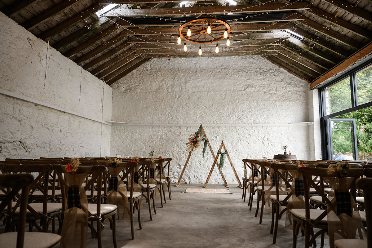 Indoor wedding ceremony setup at Blackshaw Barns with wooden chairs, simple décor and natural light from large barn windows.