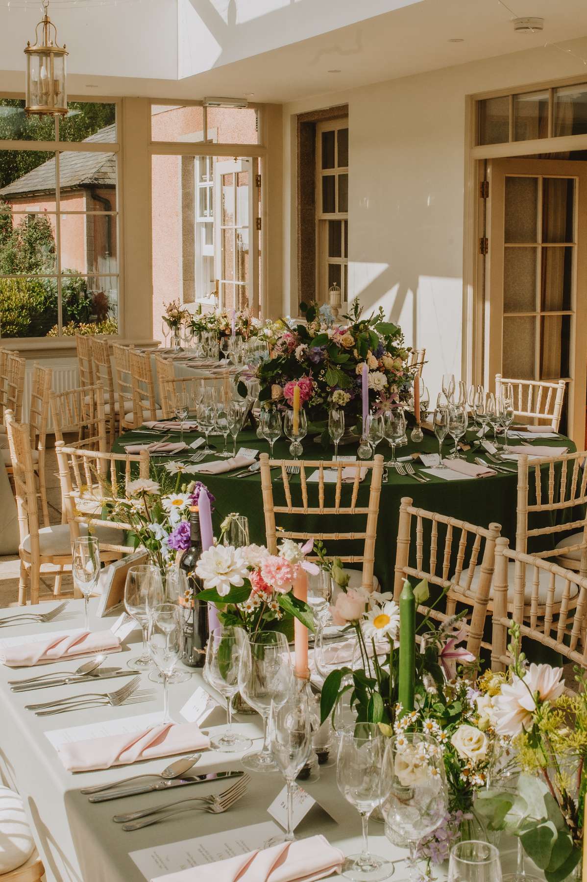 Wedding breakfast tables with colourful flowers, candles and green tablecloths at Ballogie House