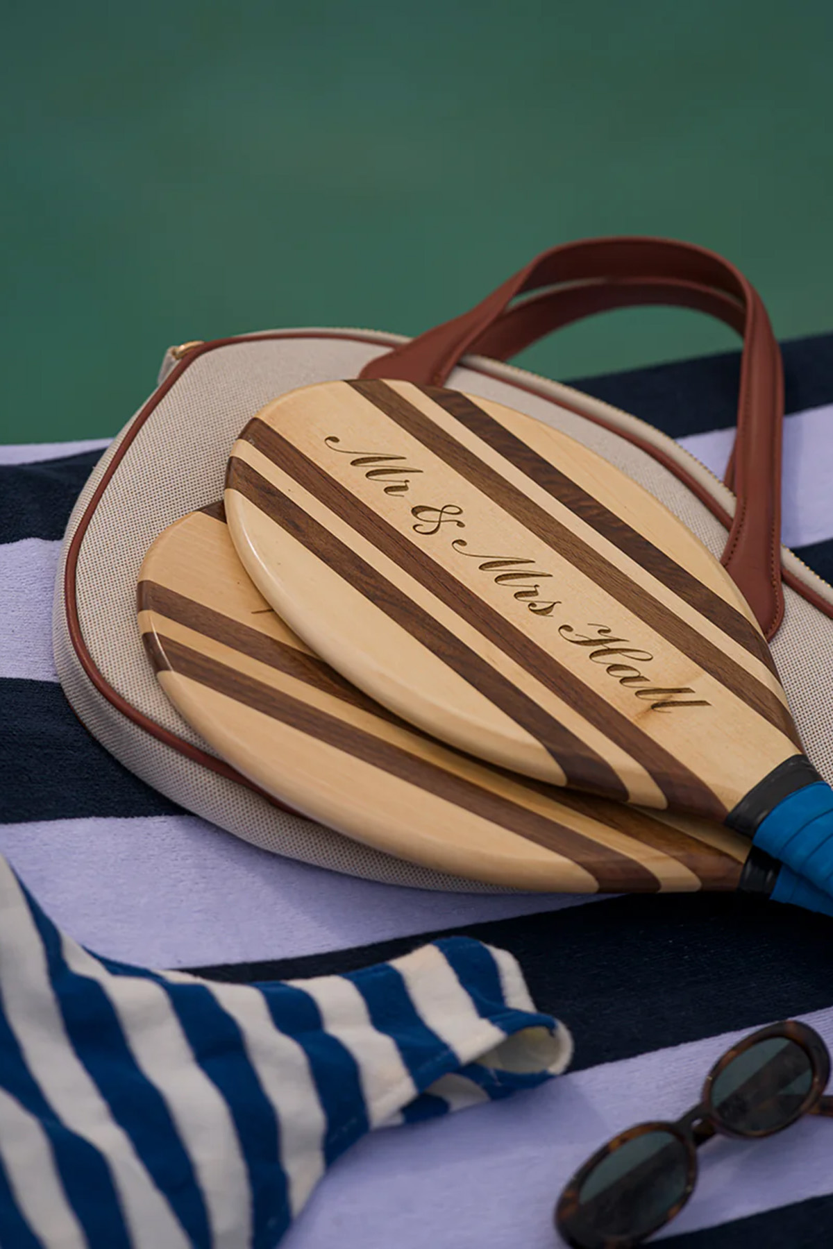 Personalised wooden bat and ball set on a striped beach towel, a playful wedding gift idea for outdoorsy couples