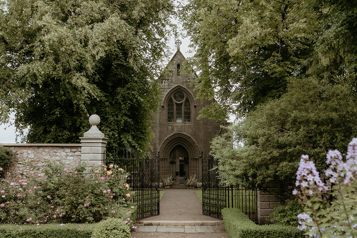 Chapel exterior at Rosebery House and Steading, Midlothian, surrounded by formal gardens and wrought iron gates.