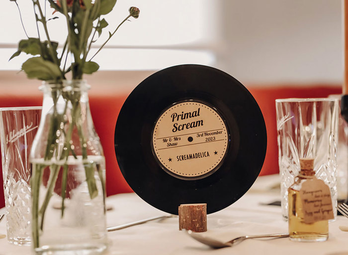 a vinyl record wedding table name in a cork surrounded by glassware