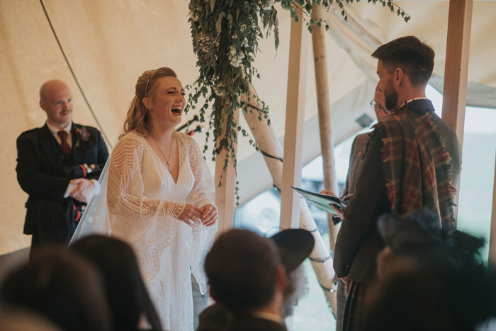Bride faces groom and laughs during ceremony