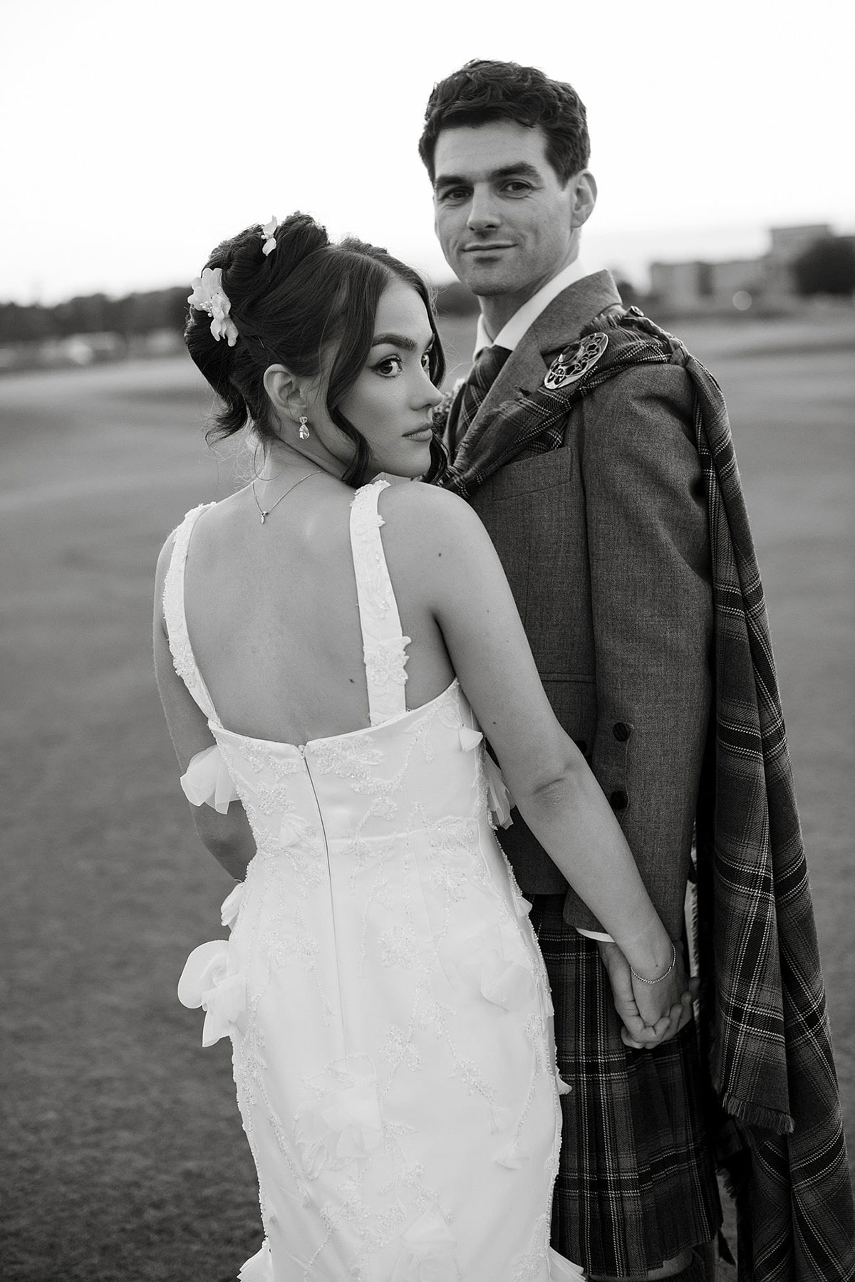 Black and white wedding portrait of bride and groom holding hands on the Old Course golf course in St Andrews.