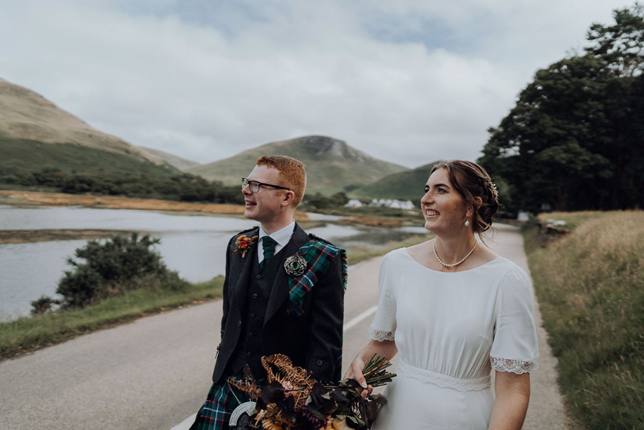 Couple walk on road beside scenic loch