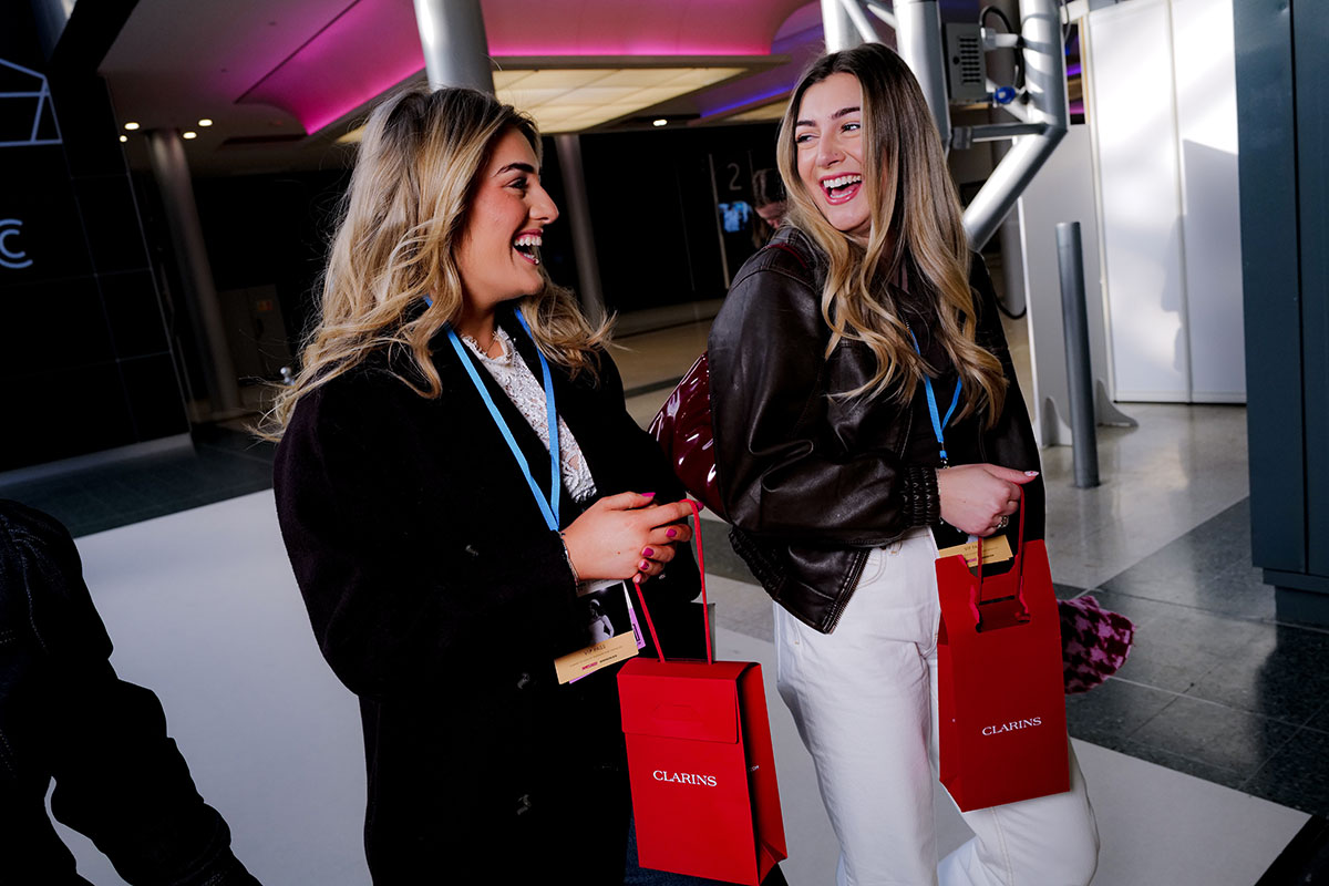 Two visitors smiling with Clarins gift bags while attending The Scottish Wedding Show.