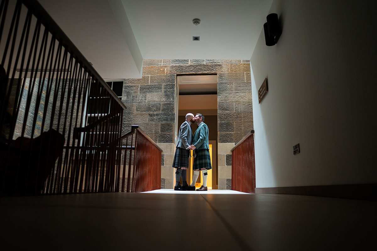 Two grooms kissing in the hallway at The Clayton Hotel