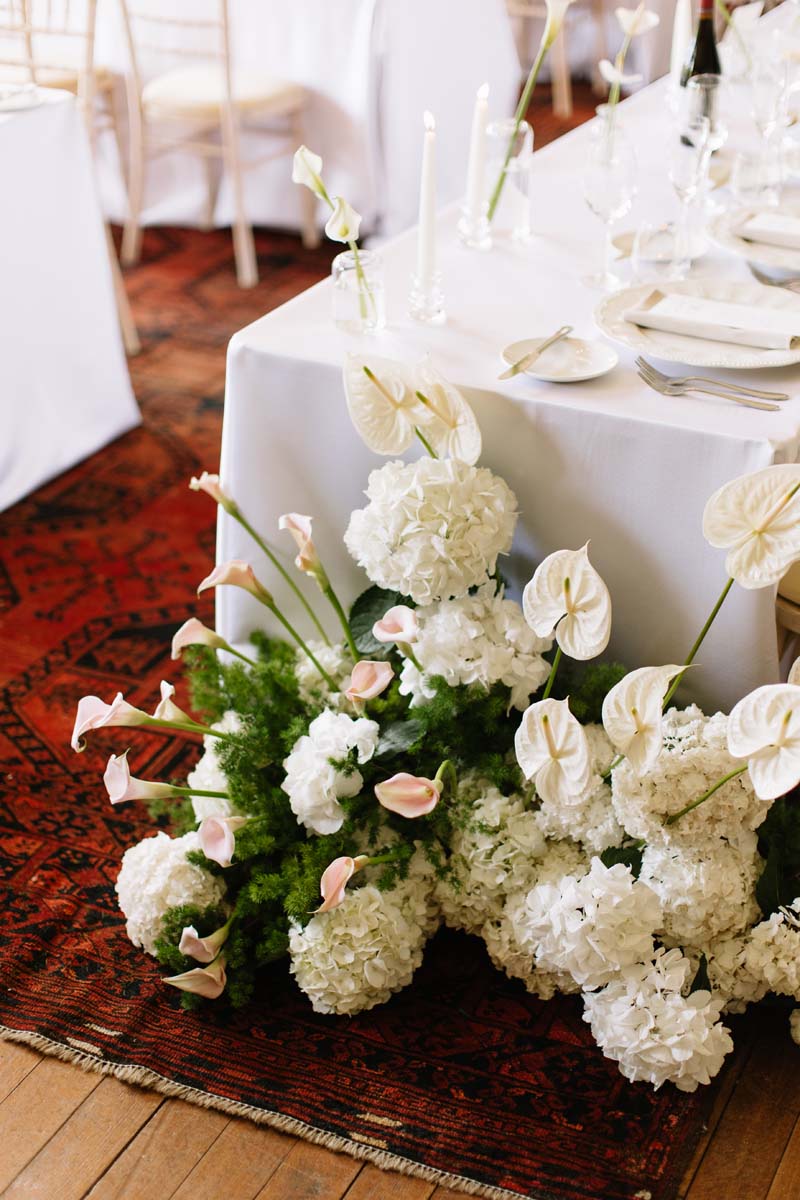 White hydrangeas, anthuriums and pale pink calla lilies decorate the wedding breakfast tables at Cambo House.