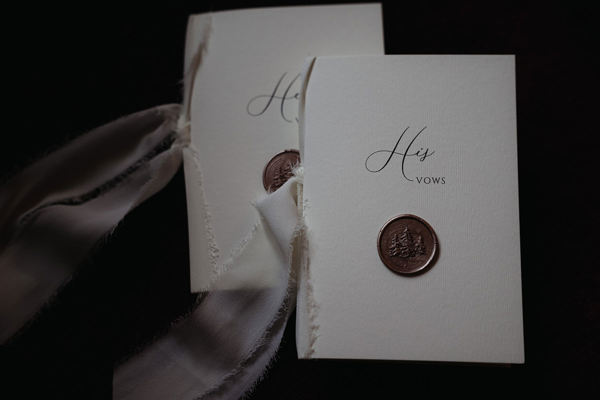 two pieces of card with wax seals and white ribbon with 'His vows' and 'Her vows' written on them