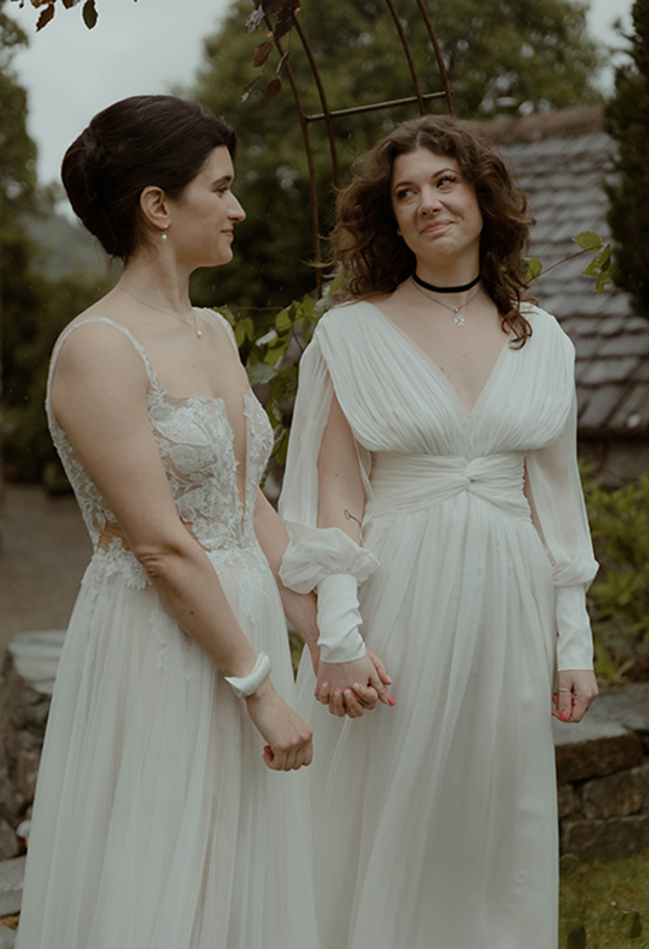 two brides hold hands and look at one another