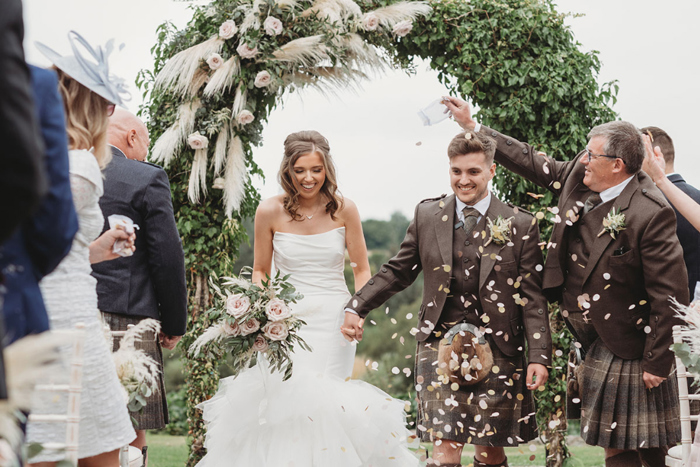 Guests throw confetti as the couple walk back up the aisle