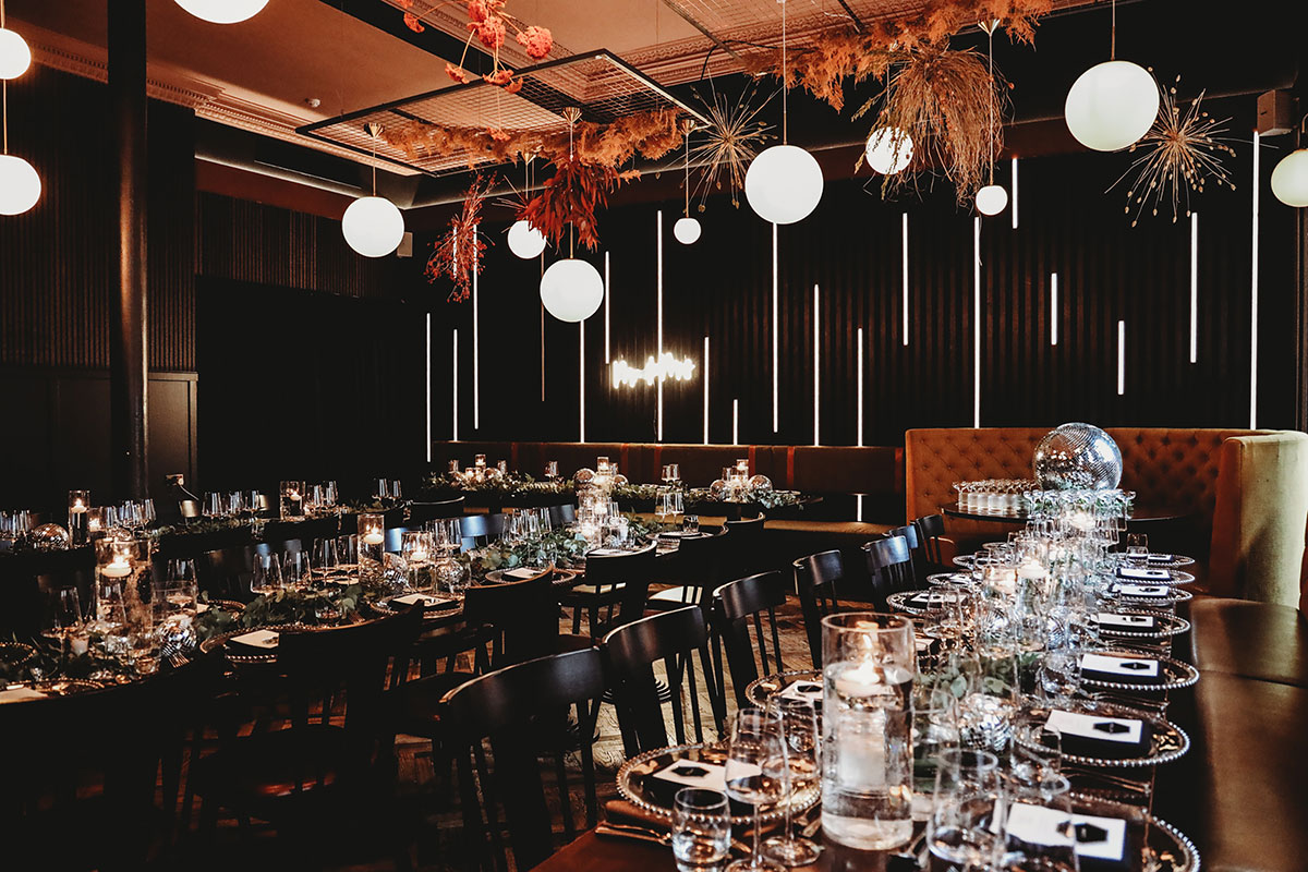 Gōst restaurant in Glasgow set for a wedding reception with dark interiors, candlelit tables, hanging lights and statement floral installations.