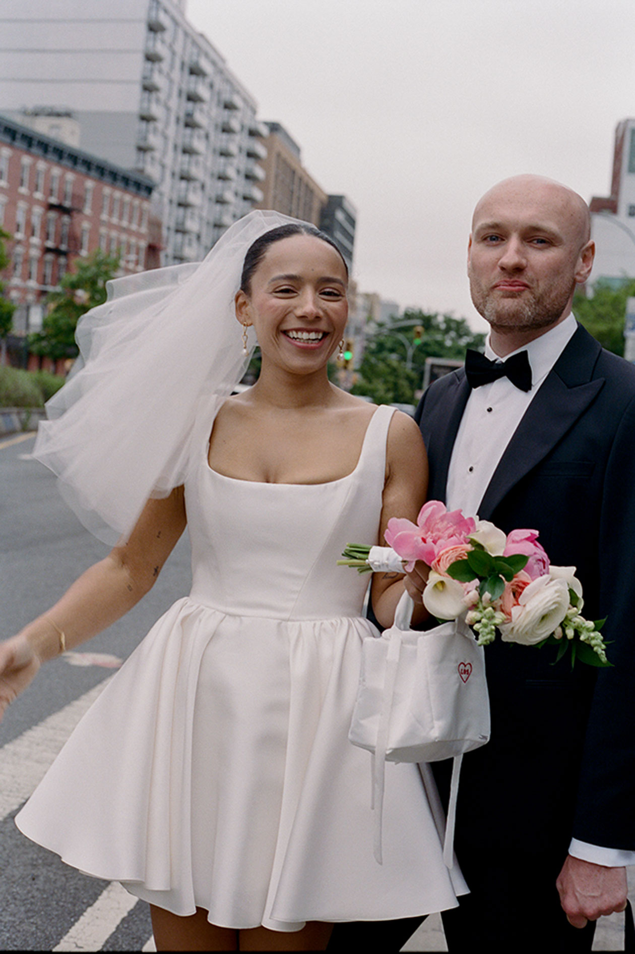 Newlyweds walking through Manhattan street bride holding bouquet after New York elopement