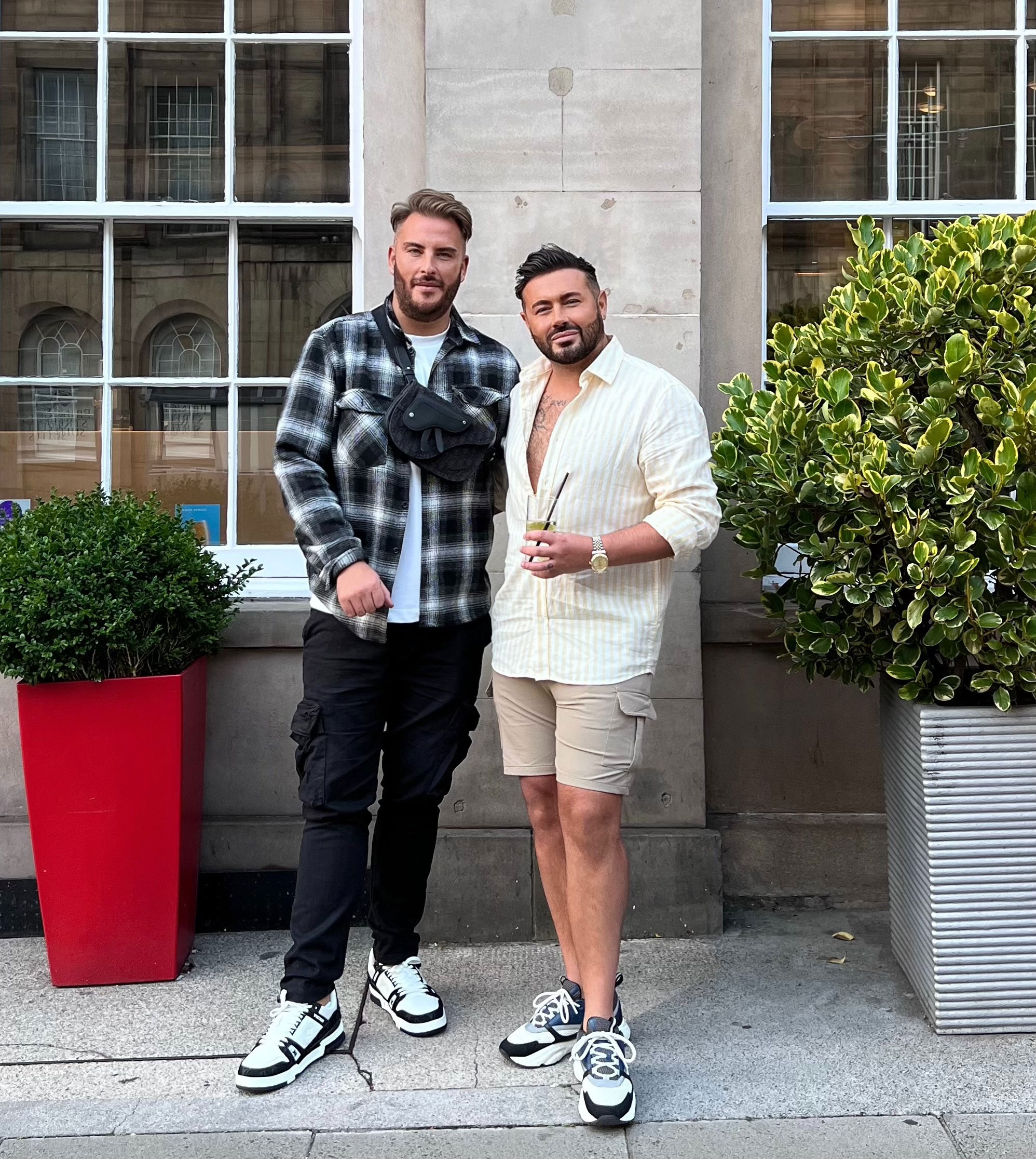 couple stand in front of bar with drinks in hand for picture
