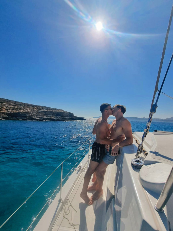 two men kissing on the deck of a yacht in the sunshine