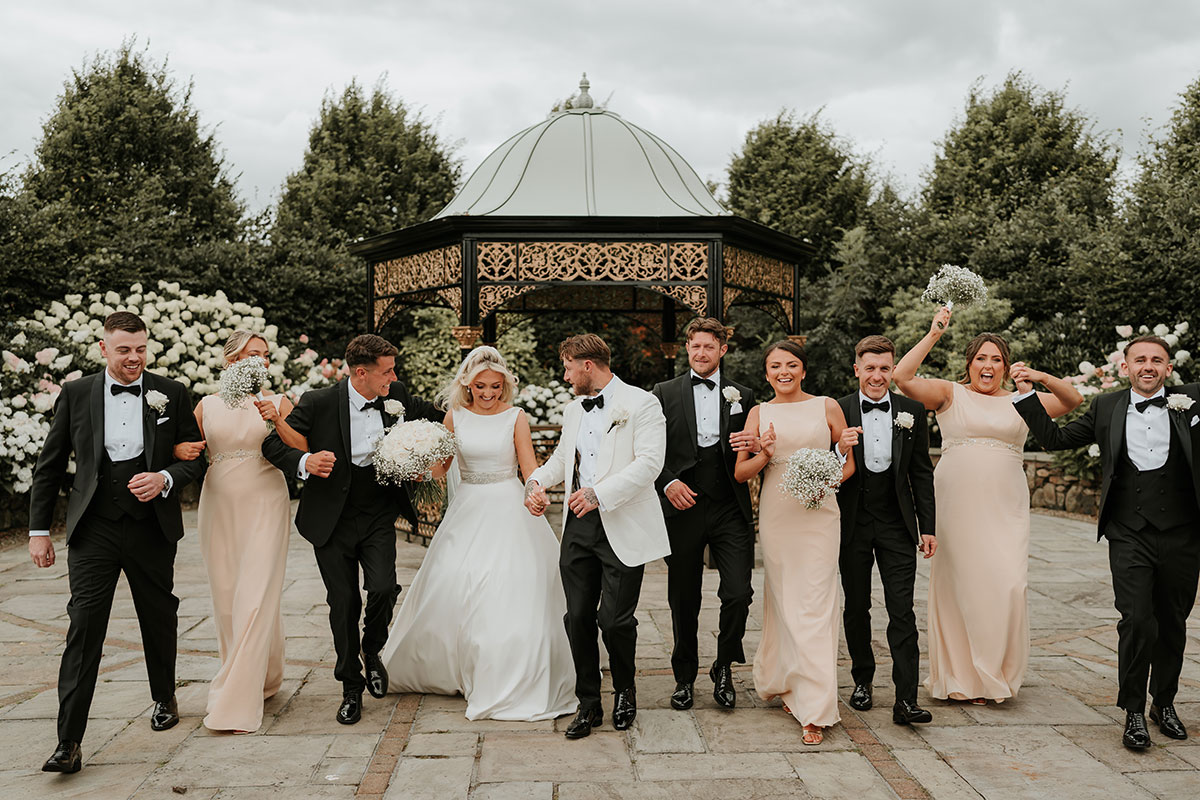 Bride, groom, bridesmaids and groomsmen walking together at Ingliston Country Club bandstand