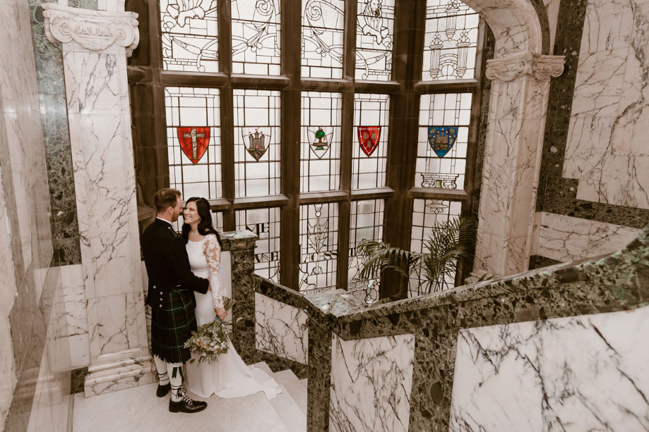 The couple gaze at each other on a marble staircase