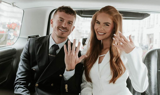 Man and woman sitting in a taxi holding their hands up to show off their wedding rings