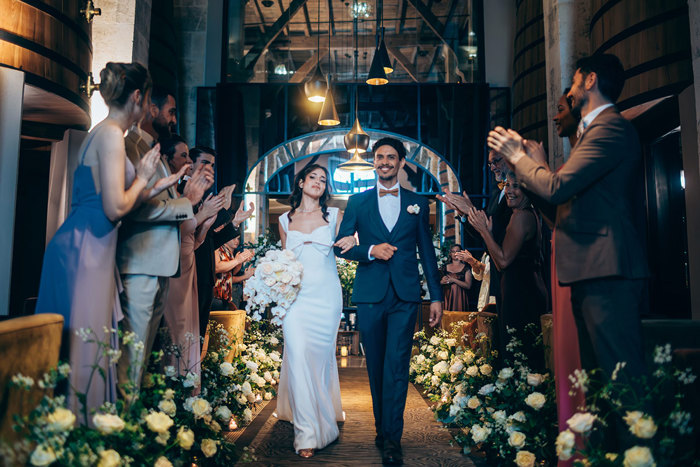 A bride and groom walking down an aisle at Chais Monnet & Spa in Cognac