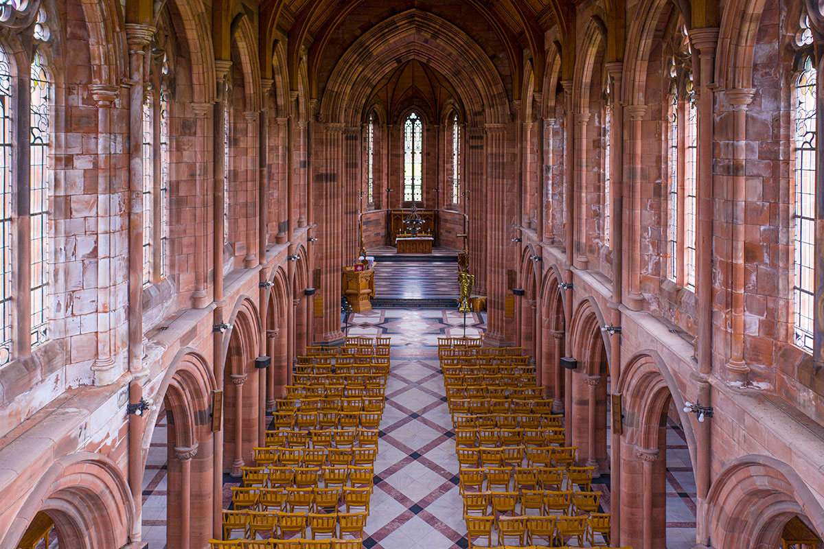 an aerial view of a large church hall filled with rows of of empty wooden chairs with an aisle formed down the middle