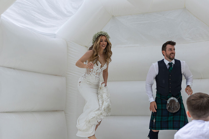 Bride and groom jump on a white bouncy castle