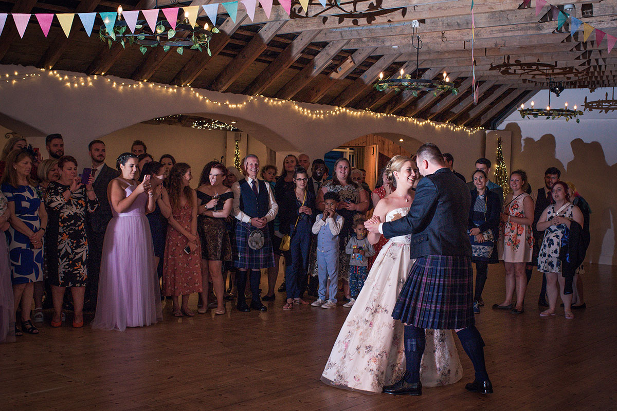 bride and groom dance together as people around them watch