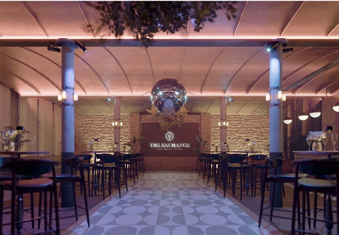 A room with bar tables and chairs and a large disco ball 