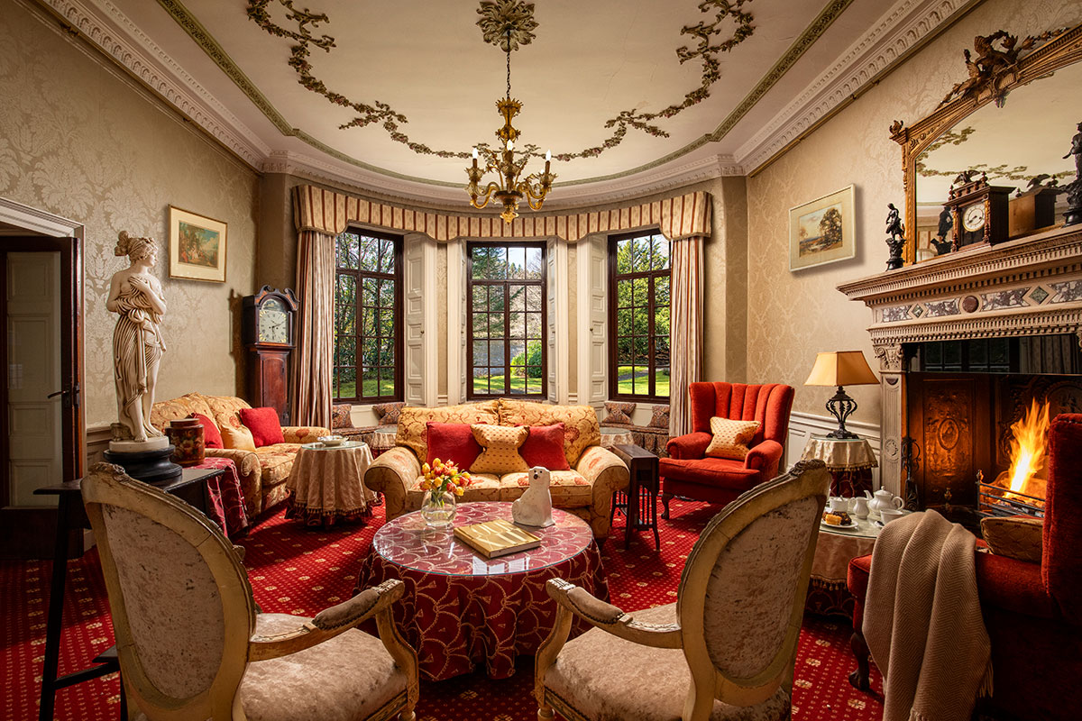 Elegant drawing room at Thackray House with ornate ceiling, bay windows, antique furniture and open fireplace.
