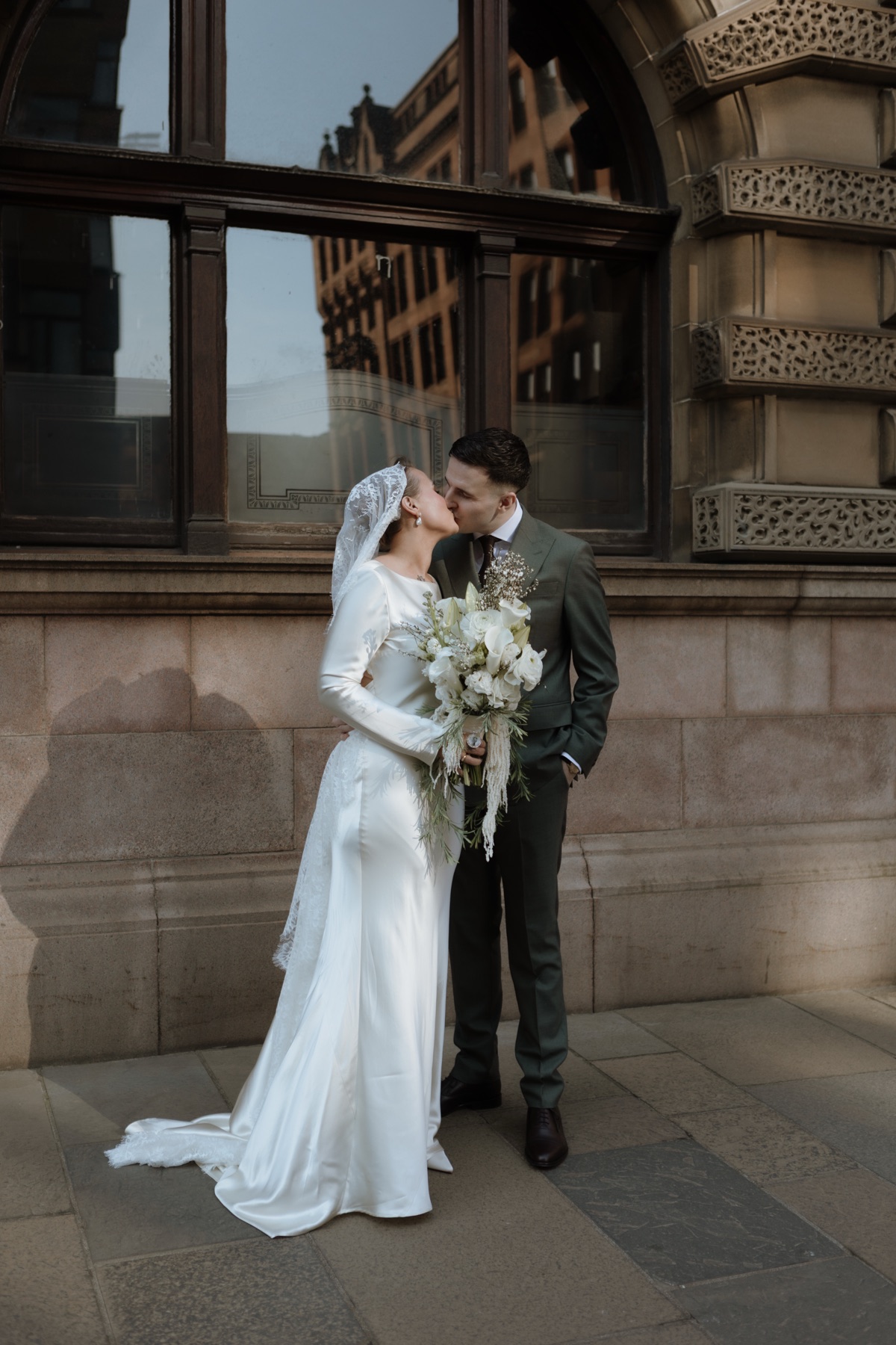 Newlyweds kissing during a city-centre wedding portrait in Glasgow.