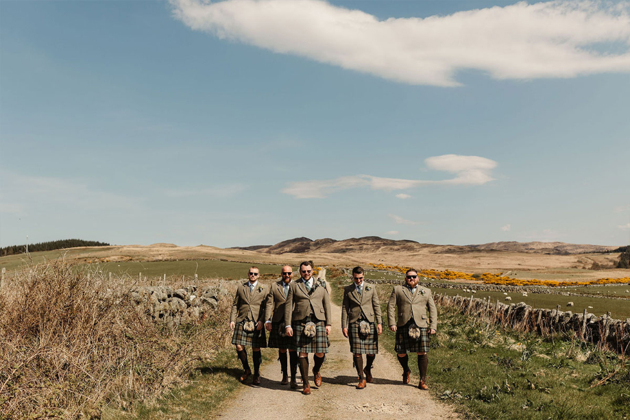 Groom and groomsmen walk down country road