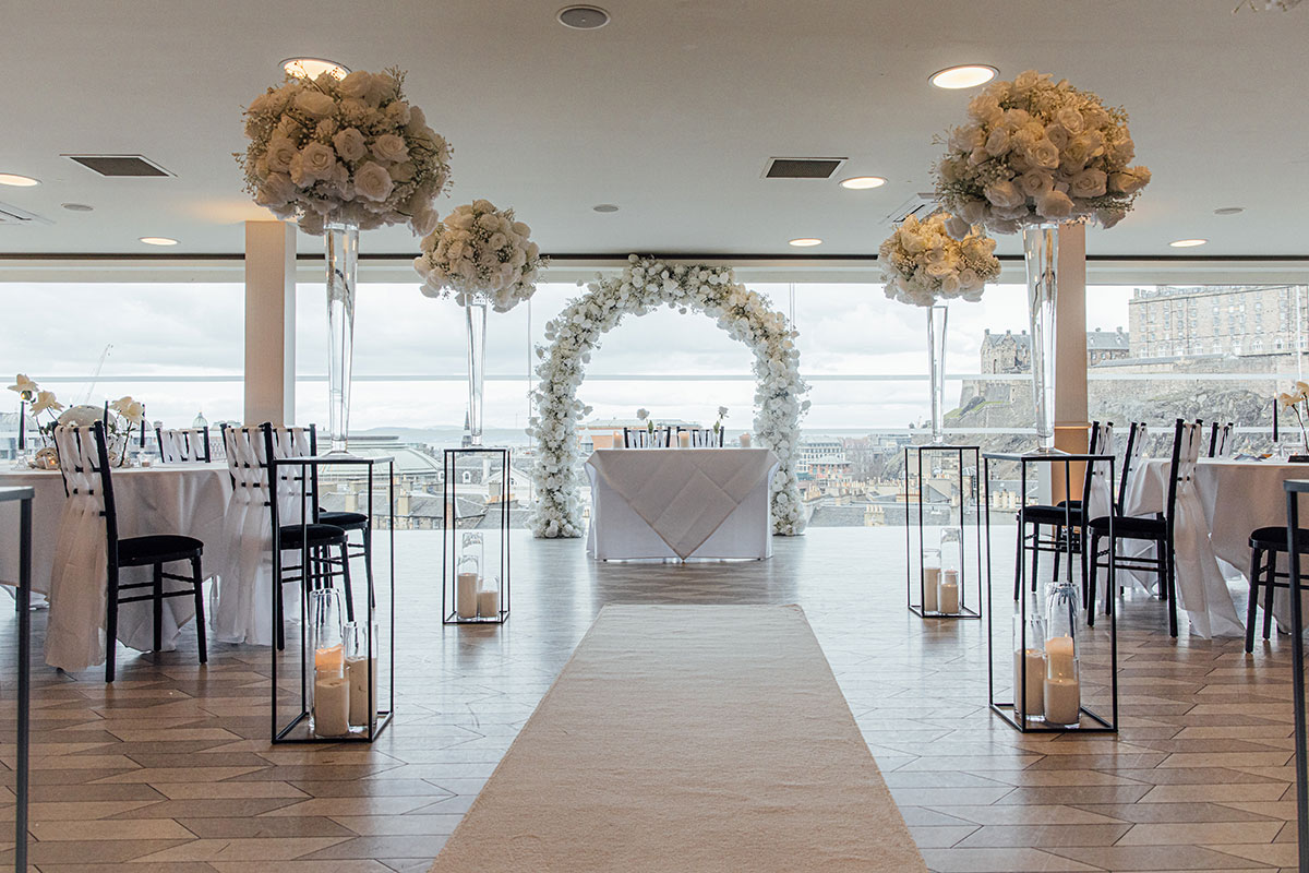 SKYBar Edinburgh wedding ceremony setup with white floral arch and Edinburgh Castle views