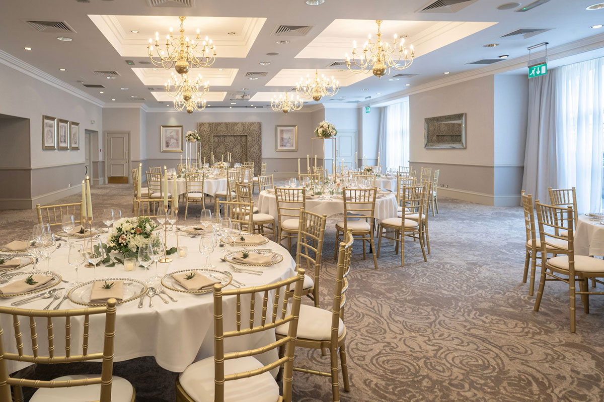 Wedding breakfast setup in the Usher Suite at Norton House Hotel & Spa with chandeliers and gold chairs