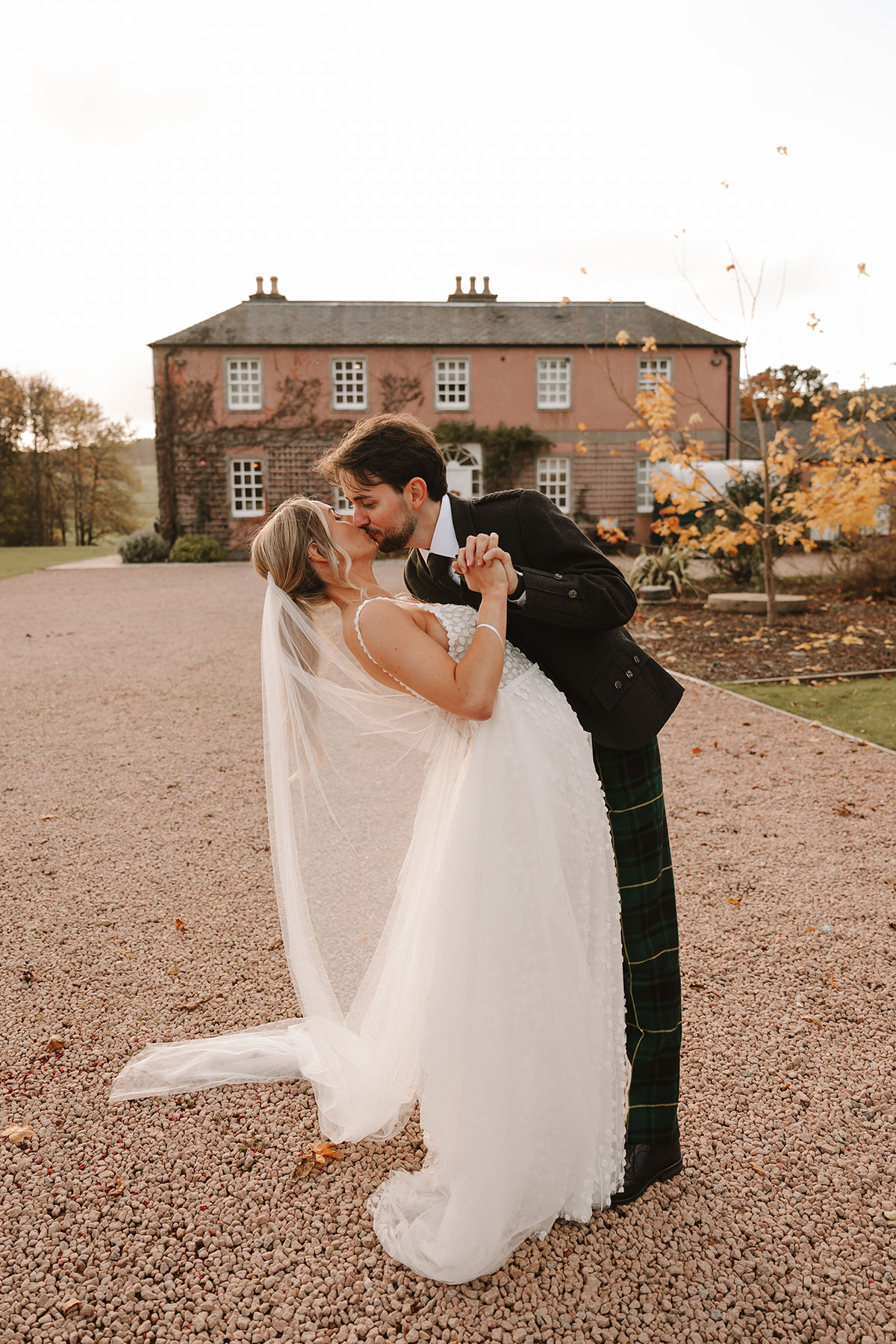 Bride and groom kissing with Ballogie House in the background