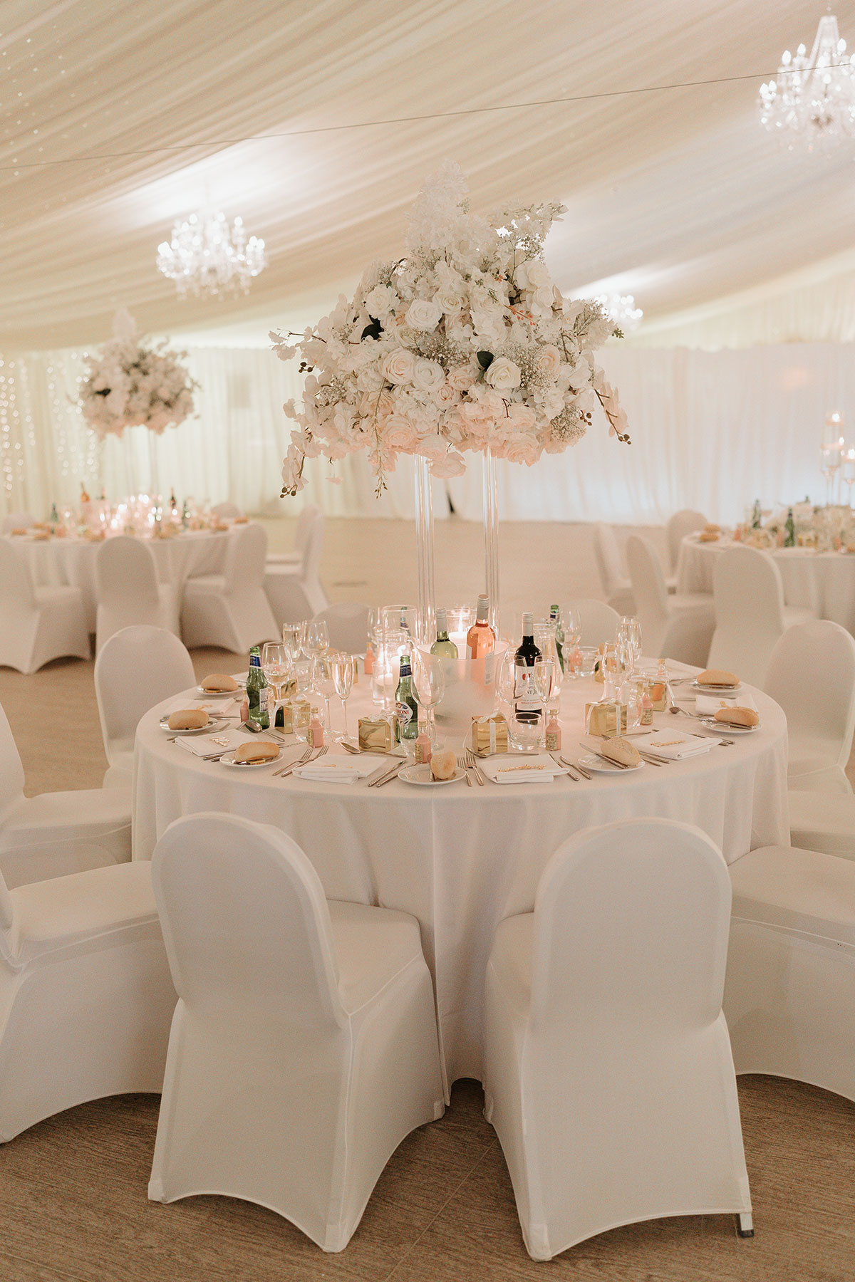 Round wedding table with tall white floral centrepiece and place settings at Ingliston Country Club