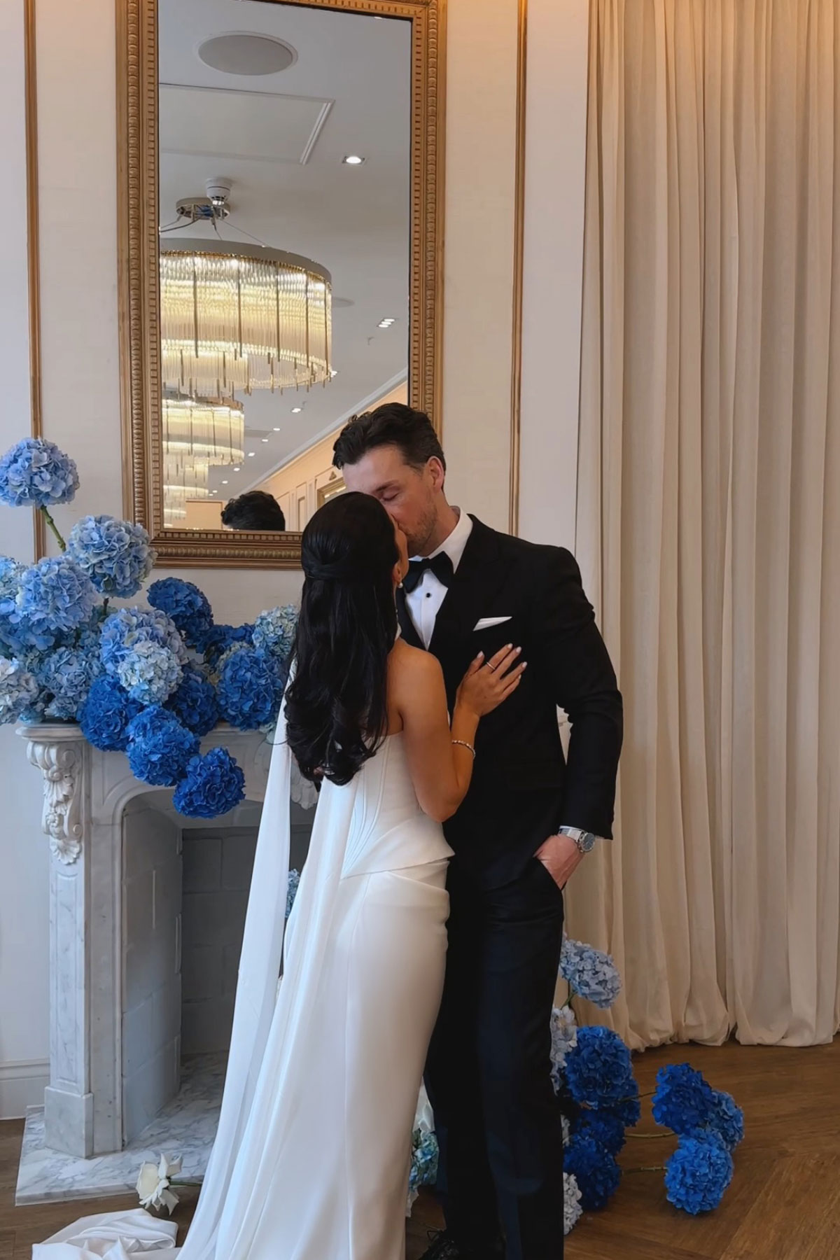 Bride and groom kissing beside blue hydrangea floral installation at The Exchange wedding venue
