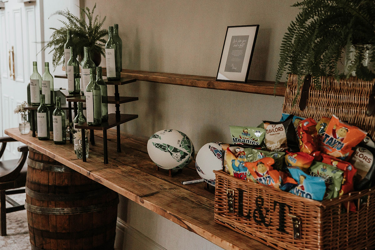 Wedding snack table display with Irish crisps, rugby balls and personalised wine bottles at Norton House Hotel wedding