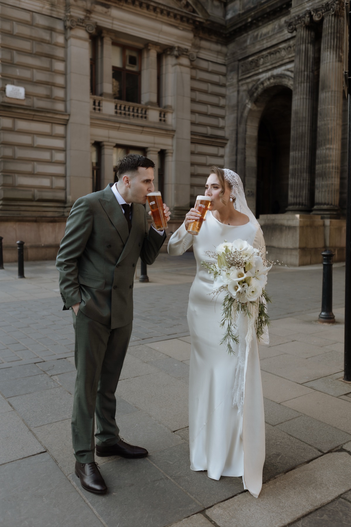 Newlyweds drinking pints together during their Glasgow city-centre wedding portraits.