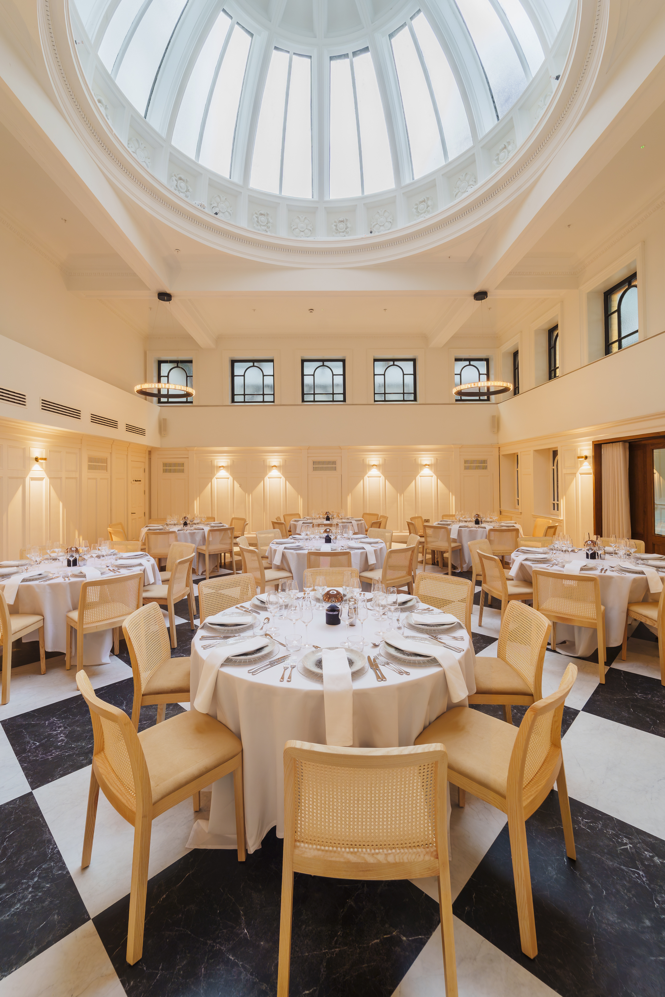The Collector's Hall set up for a wedding dinner with round tables and wooden rattan chairs