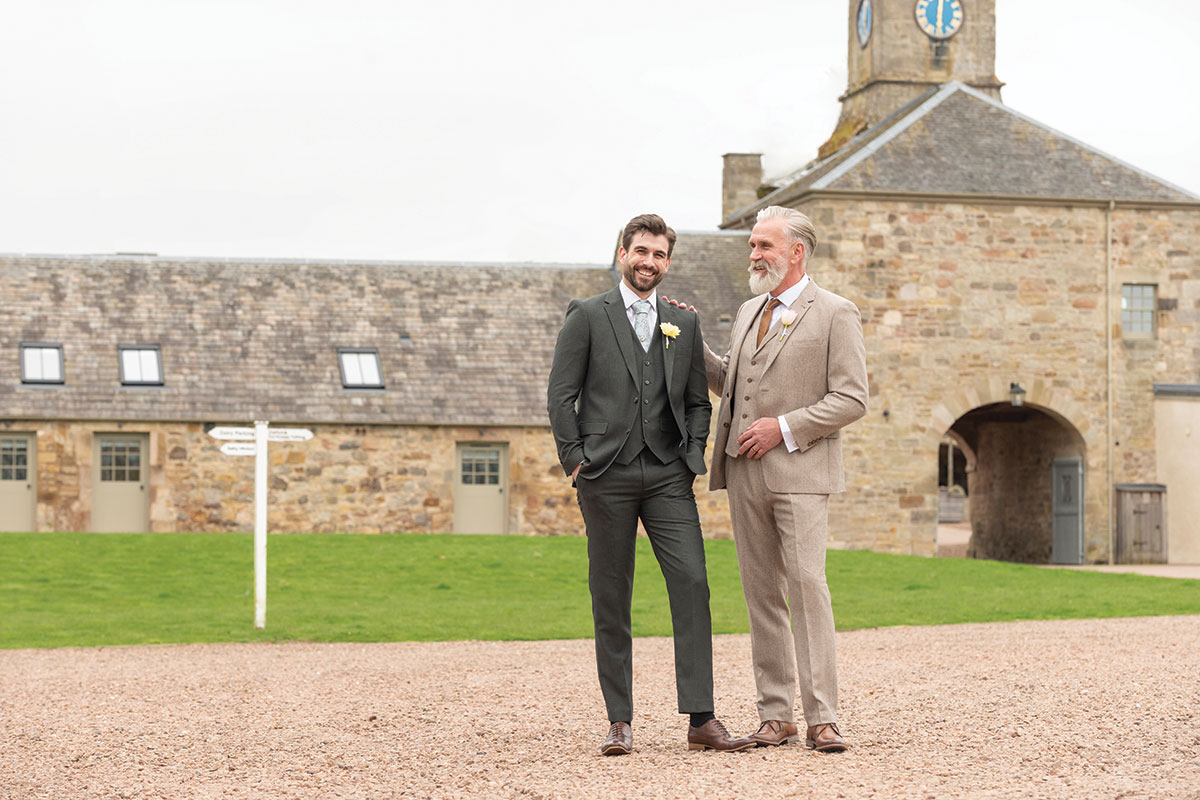two men in Slater Menswear suits standing outside Rosebery Steading
