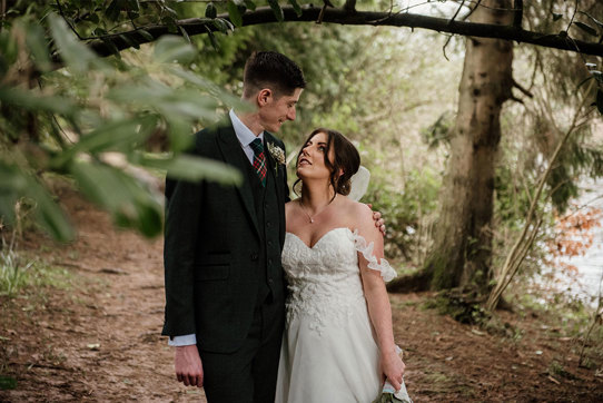 bride and groom looking at each other in a woodland