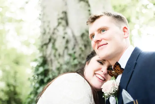 Bride with head on grooms shoulder, both smiling