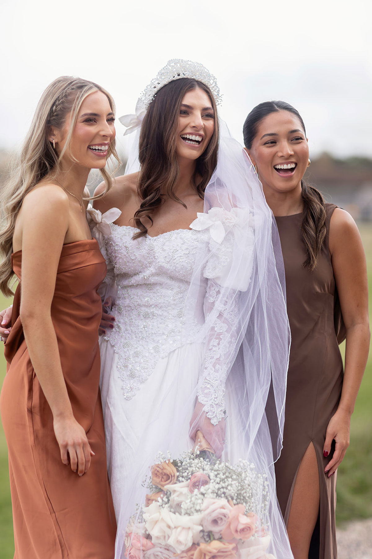 A bride with two bridesmaids beside her dressed in brown dresses