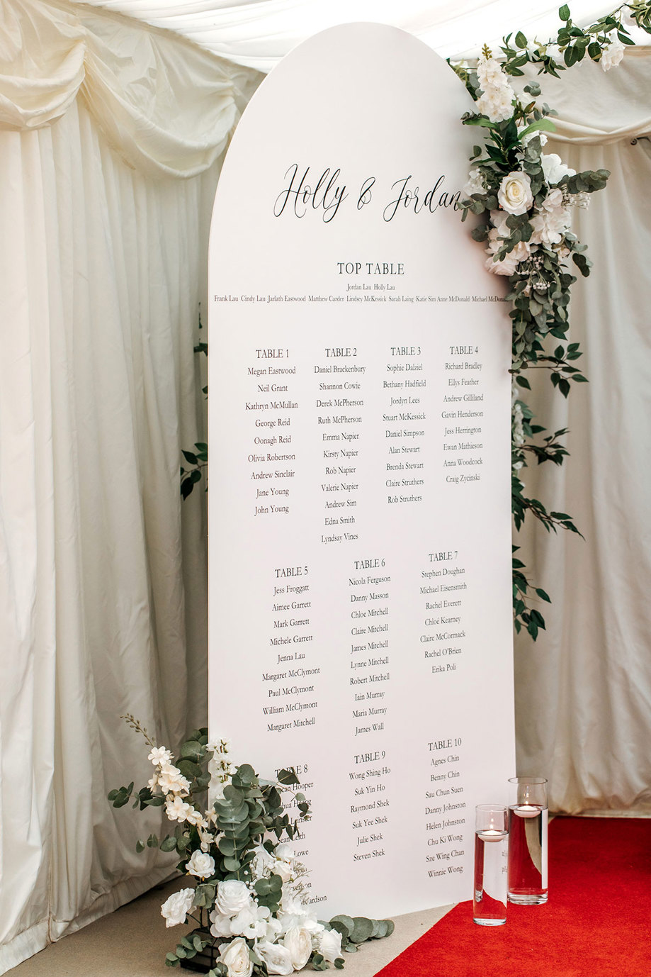 white table sign with guests names for wedding breakfast with white and green foliage around it
