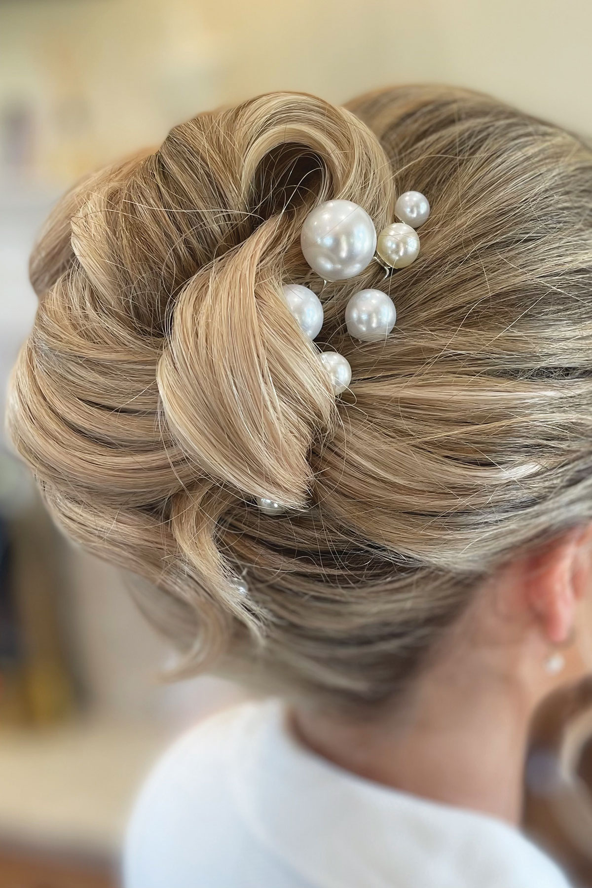 Close-up of an elegant bridal updo with soft twisted details, finished with pearl hair accessories of varying sizes