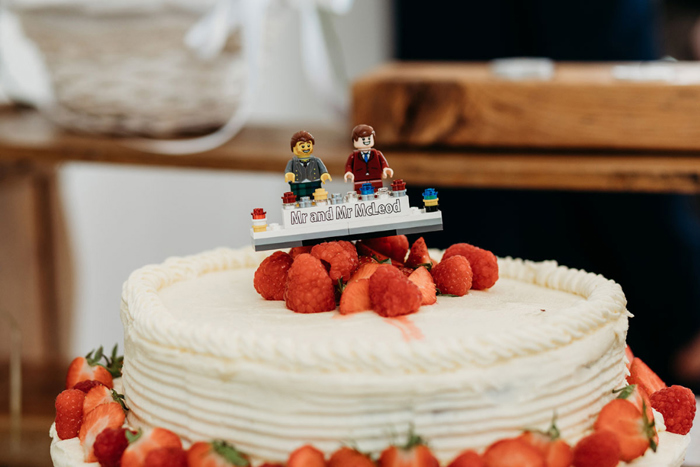 White wedding cake with strawberries and lego cake topper on top